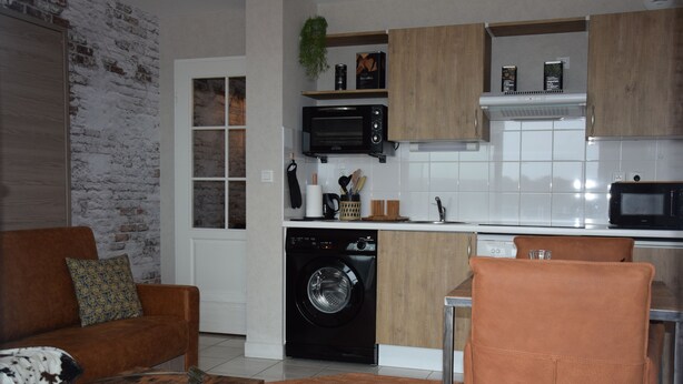 A compact living space with a sofa, a coffee table, a washing machine, and a microwave in the kitchen area.