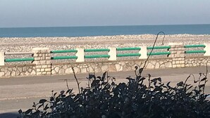 A coastal road with a stone barrier and green railings.
