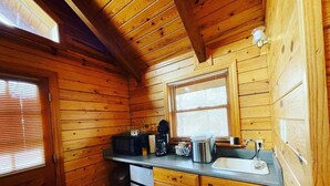 Una cucina compatta con pareti in legno, un forno a microonde integrato, una moka e un lavello.