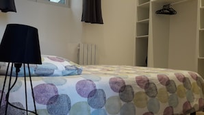 Un dormitorio con cama, radiador, armario y perchero.