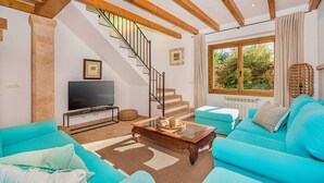 Un salon avec un escalier, un téléviseur et une grande fenêtre donnant sur un paysage verdoyant.