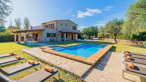 Une maison en pierre avec une piscine et un espace extérieur aménagé pour se détendre.