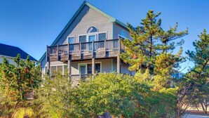 A two-story building with a balcony on the upper floor, surrounded by trees. - June 27-July 4th is OPEN. CHECK THE DISCOUNTED RATES. (Corolla)