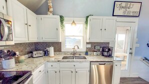 A modern kitchen with white cabinets, a stainless steel dishwasher, a coffee maker, and a toaster. - June 27-July 4th is OPEN. CHECK THE DISCOUNTED RATES. (Corolla)