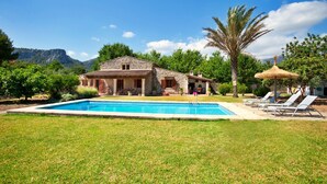 A stone villa with a swimming pool, surrounded by lush greenery and a mountain backdrop. - Finca Gloria for 4 persons with pool (Pollensa)