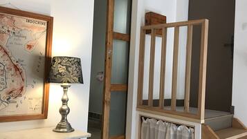 Um quarto com uma escada de madeira, um mapa na parede e uma luminária sobre uma mesa.