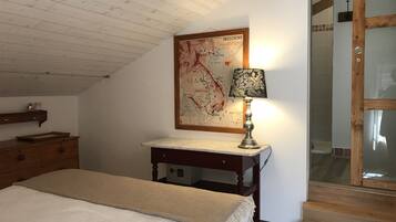 Une chambre à coucher avec un lit, une table de chevet en bois, une carte accrochée au mur et une lampe.