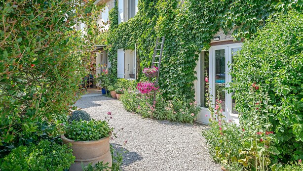 A garden pathway leading to a building with a white facade and windows. - Le Mas Mellou (Orange)