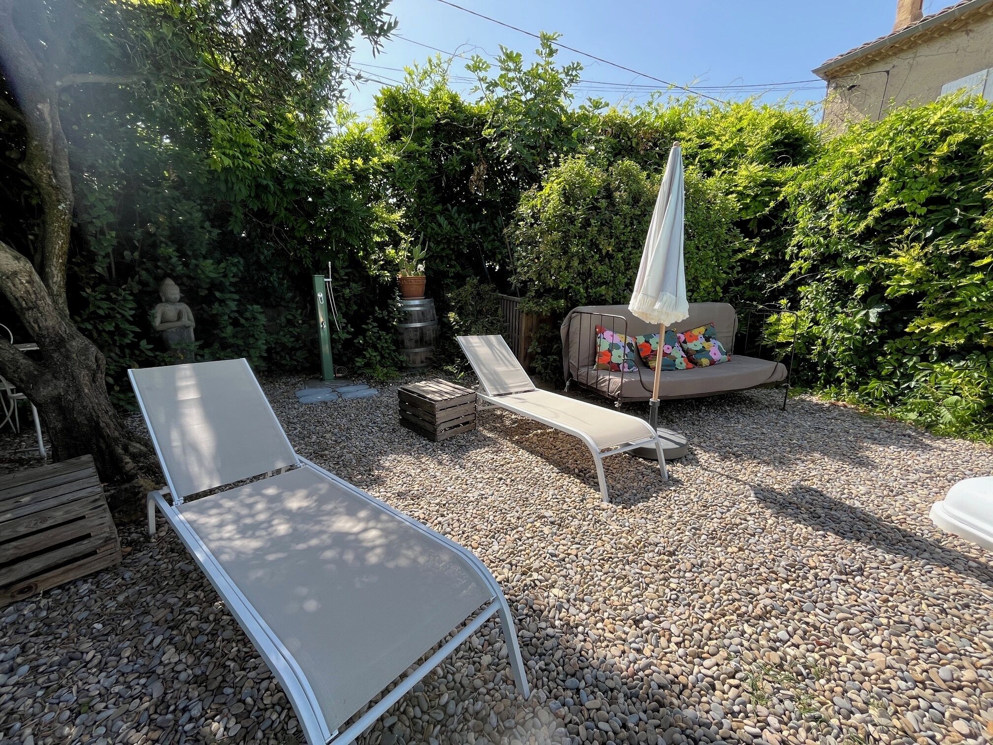 A garden with two lounge chairs, a sofa, and a statue.