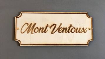 Ein Holzschild mit dem Schriftzug 'Mont Ventoux' vor einem schlichten Hintergrund.