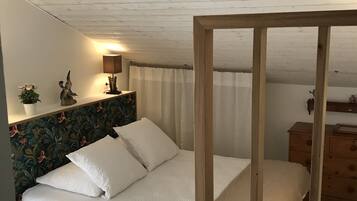 A bedroom with a wooden headboard, a bed with white bedding, a nightstand with a lamp, and a dresser.