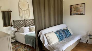 A bedroom with a bed, a bedside table, a lamp, a dreamcatcher, a map on the wall, and a patterned floor.