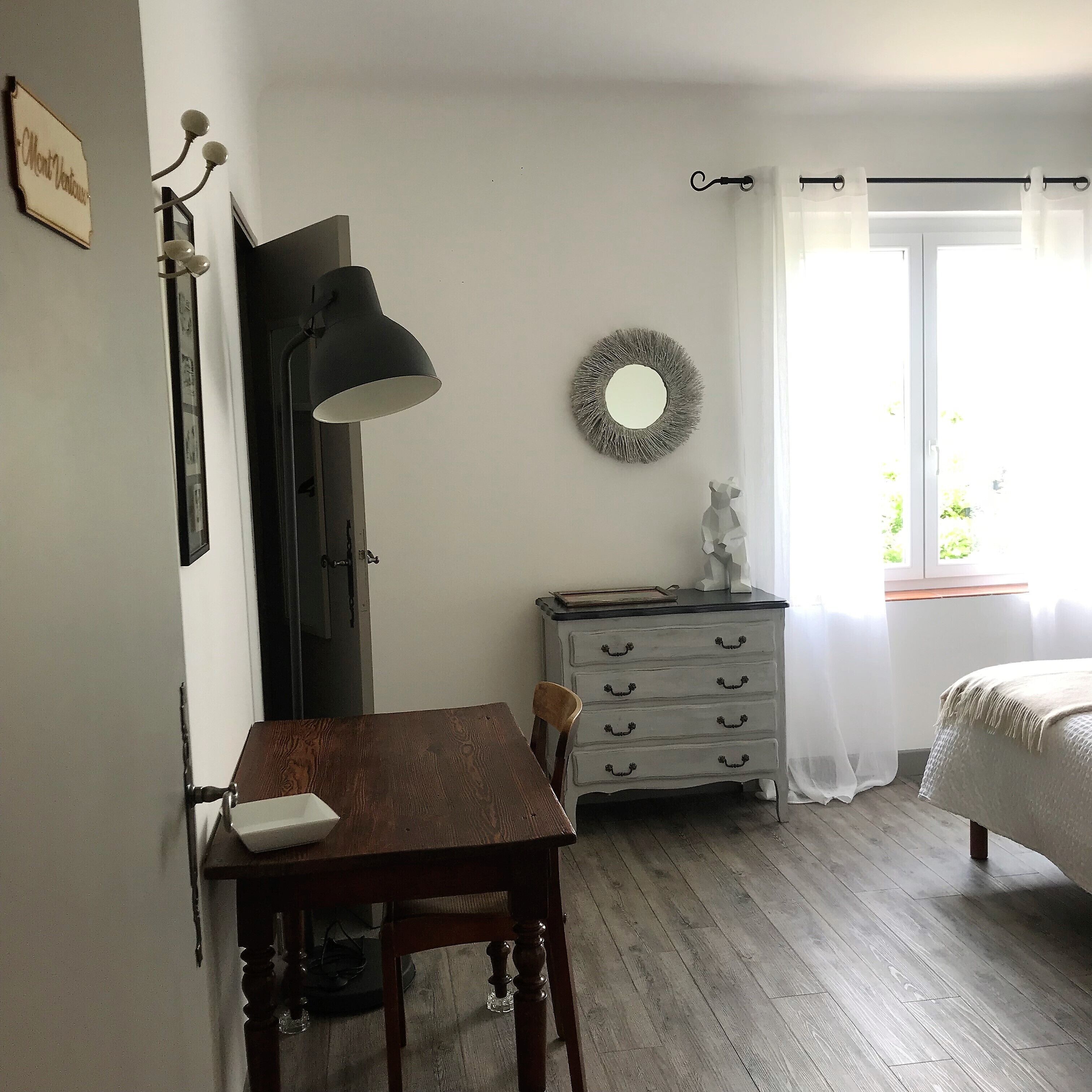 Une chambre à coucher avec une table en bois, une commode, un miroir et un lit.