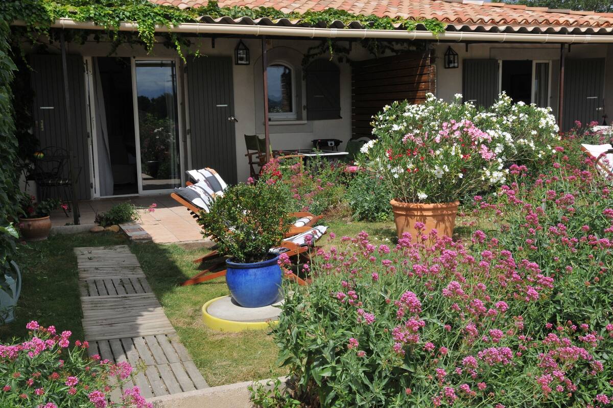 A covered patio with a wooden deck, outdoor seating, and potted plants.
