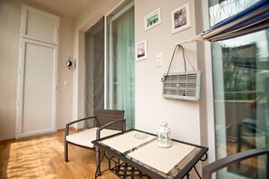 Un balcon avec deux chaises, une table, une lanterne et un climatiseur fixé au mur.