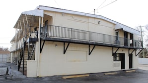 A two-story building with a balcony, a stairway, and a garage door. - Royal Budget Inn (Redford)
