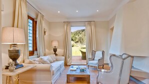 A spacious living room with a sofa, armchairs, a coffee table, and a view of the garden.