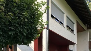 A modern two-story building with a red exterior and a covered outdoor seating area. - With us (Tittling)