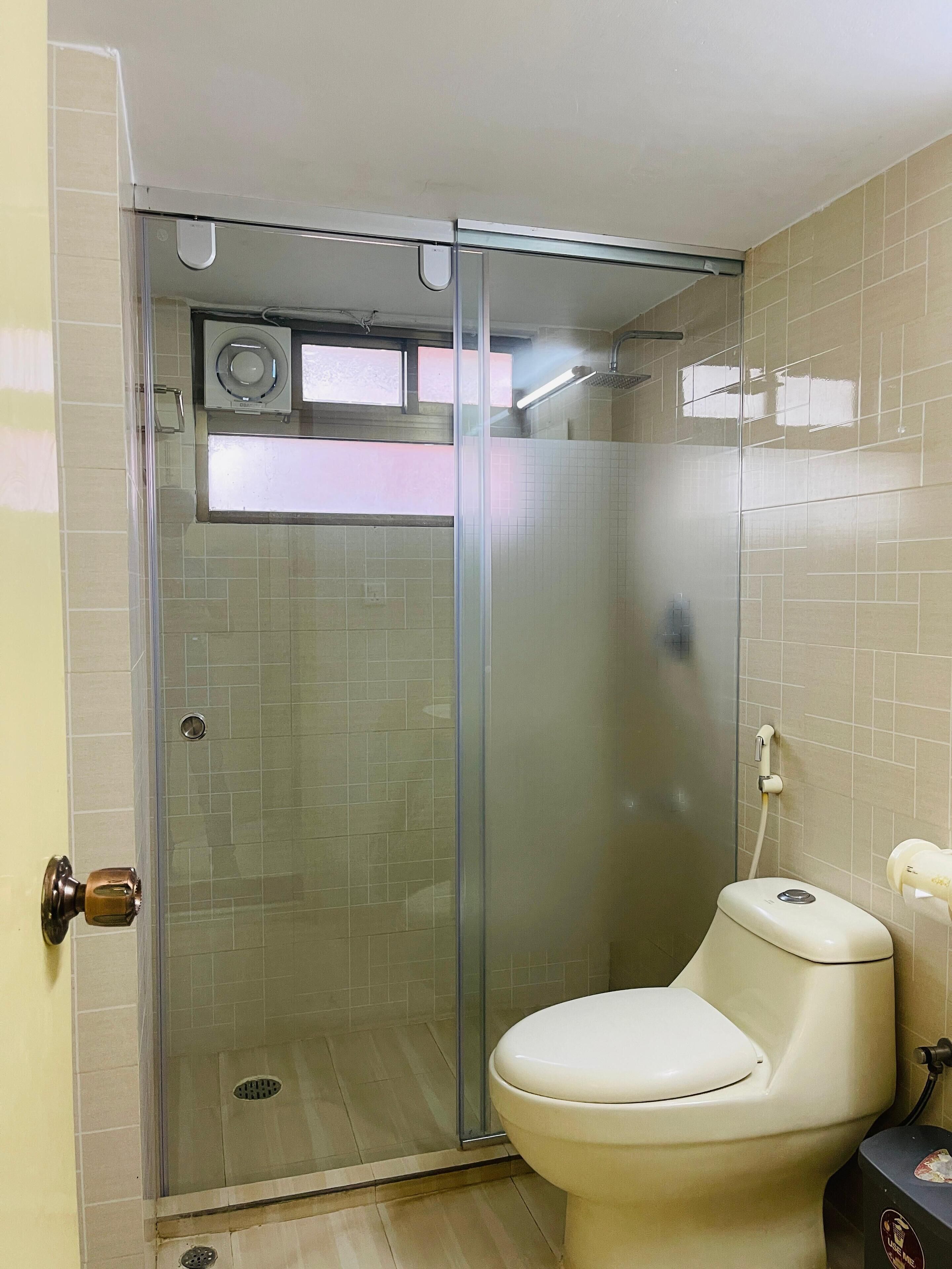 Une salle de bain avec une douche à parois de verre, des toilettes et un lavabo.