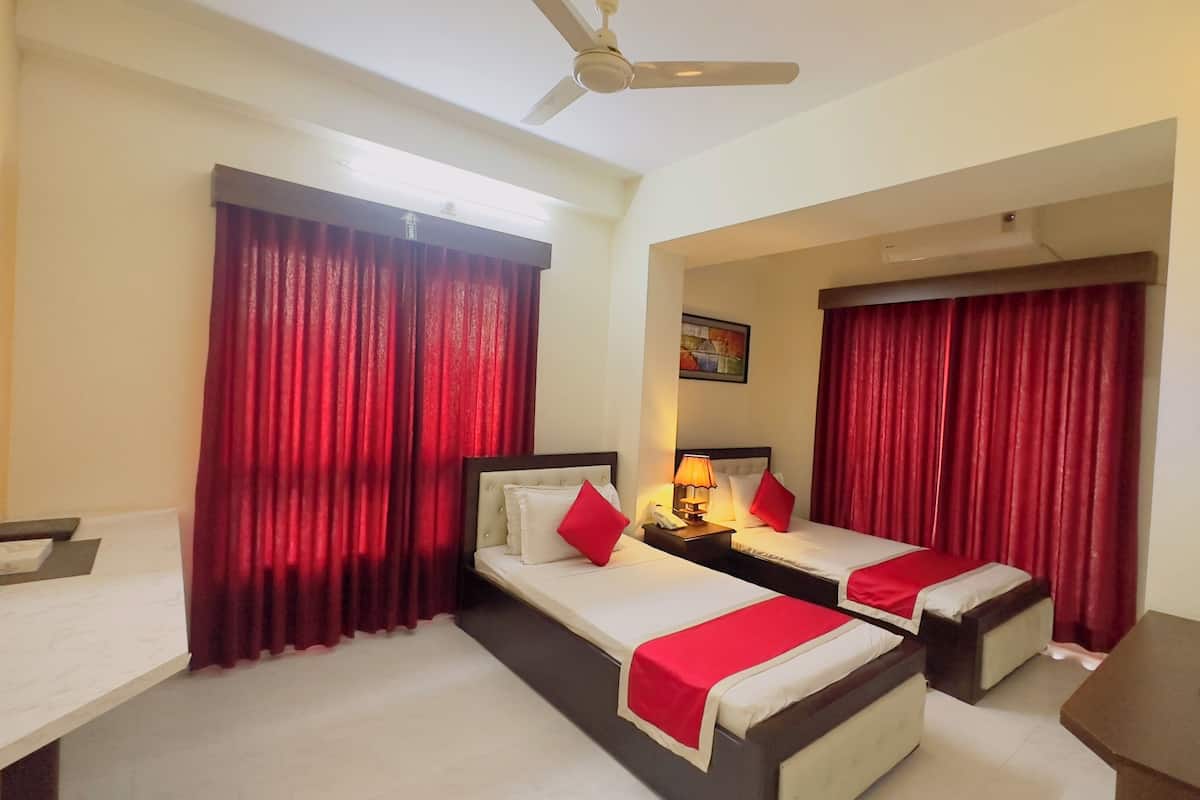 A hotel room with two beds, a desk, and a ceiling fan.
