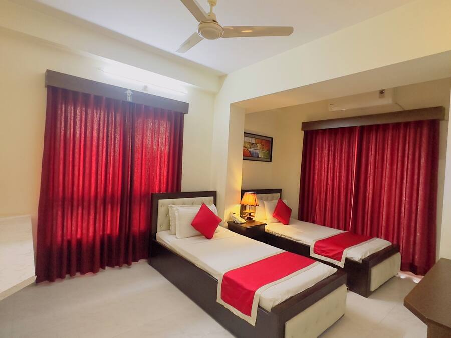 A hotel room with two beds, a desk, and a ceiling fan.