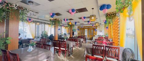 Un restaurante con mesas y sillas de madera, decorado con globos y plantas.