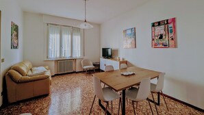 A room with a dining table, chairs, a sofa, a television, and artwork on the walls. - Residence Parco Ducale (Parma)