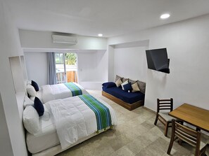 A hotel room with two beds, a TV, a wooden table, and a chair. - Hotel Plaza Huatulco Bungalows (Santa María Huatulco)