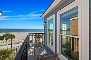 A beachfront property with a balcony overlooking the ocean.