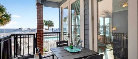 A balcony with a table, chairs, and a view of the beach.