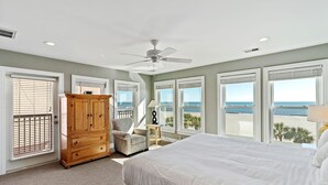 Une chambre à coucher avec un grand lit, une armoire en bois, une chaise et un ventilateur de plafond.