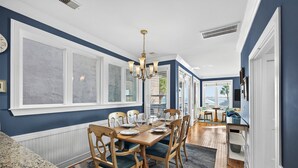 Un coin repas avec une table en bois dressée pour six personnes, entourée de chaises à l’assise verte.