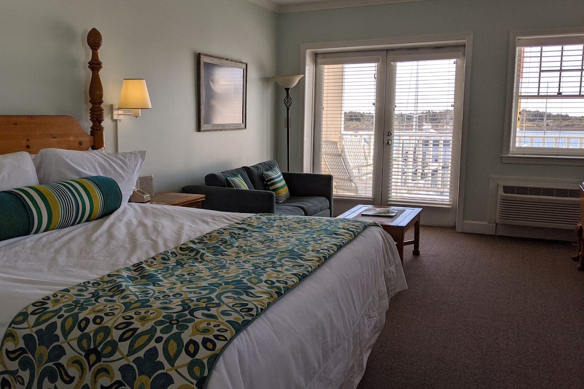 Une chambre d’hôtel avec un grand lit, un canapé, un bureau et une vue sur la ville par les fenêtres.