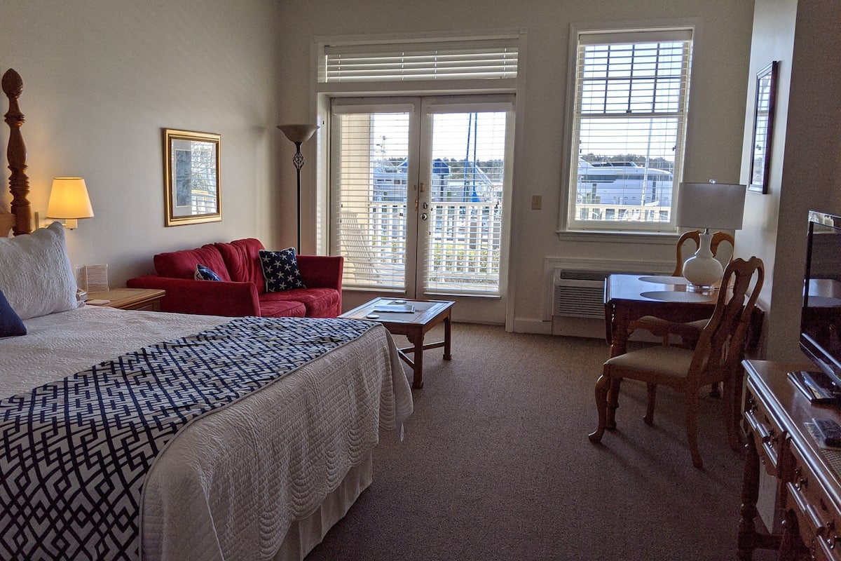 Une chambre d’hôtel avec un grand lit, un canapé rouge, une petite table et un téléviseur.
