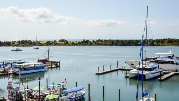 A marina with multiple boats docked, a ferry service sign, and a docked yacht. - Inlet Inn NC (Beaufort)