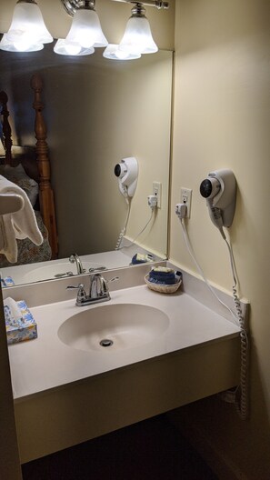 A bathroom with a large mirror, two sinks, a towel rack, and a hairdryer.