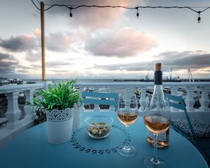 A table with a bottle of wine, two glasses, a bowl of nuts, and a potted plant on a blue tablecloth. - Luxury home, centrally located with a beautiful balcony overlooking the marina. (Ponta Delgada)