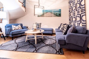 A modern living room with a blue sofa, a round coffee table, and a patterned rug.