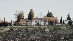 A white building with a tiled roof, surrounded by trees and a rocky field. - Country home in Dosbarrios, Toledo (Dosbarrios)