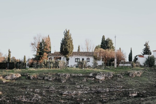 A white building with a tiled roof, surrounded by trees and a rocky field. - Country home in Dosbarrios, Toledo (Dosbarrios)