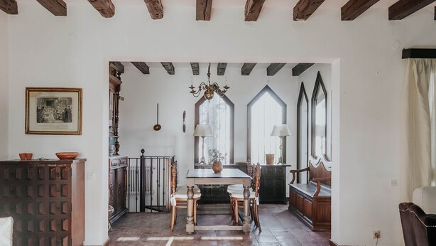 A dining area with a wooden table and chairs, a chandelier, and a view through tall windows. - Country home in Dosbarrios, Toledo (Dosbarrios)