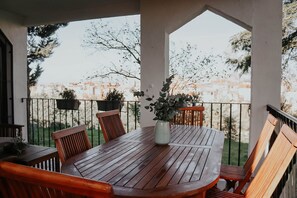 A wooden table with chairs on a balcony, surrounded by a railing, with potted plants and a view of buildings. - Country home in Dosbarrios, Toledo (Dosbarrios)