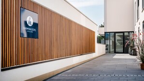 A modern building with a wooden slatted facade and a sign for Haimhausers Hotel Garni. - HAIMHAUSERS Hotel Garni (Haimhausen)