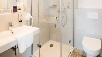Un baño moderno con ducha de vidrio, lavamanos blanco y retrete.