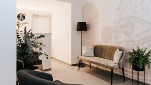 A modern interior with a sofa, chairs, a floor lamp, and a wall with a cityscape mural. - HAIMHAUSERS Hotel Garni (Haimhausen)