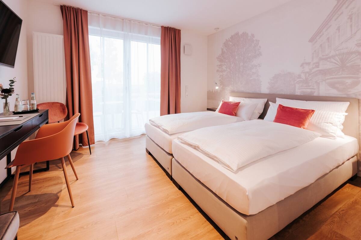 A hotel room with a bed, a desk, and a chair.