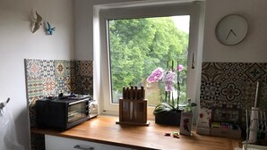 Une cuisine avec une fenêtre, un grille-pain, un bloc à couteaux et une plante.