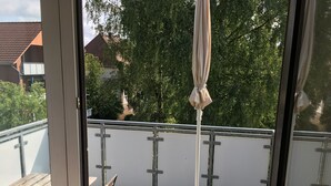 Un balcon doté d’une rambarde en métal, d’un sol carrelé et d’un banc en bois.