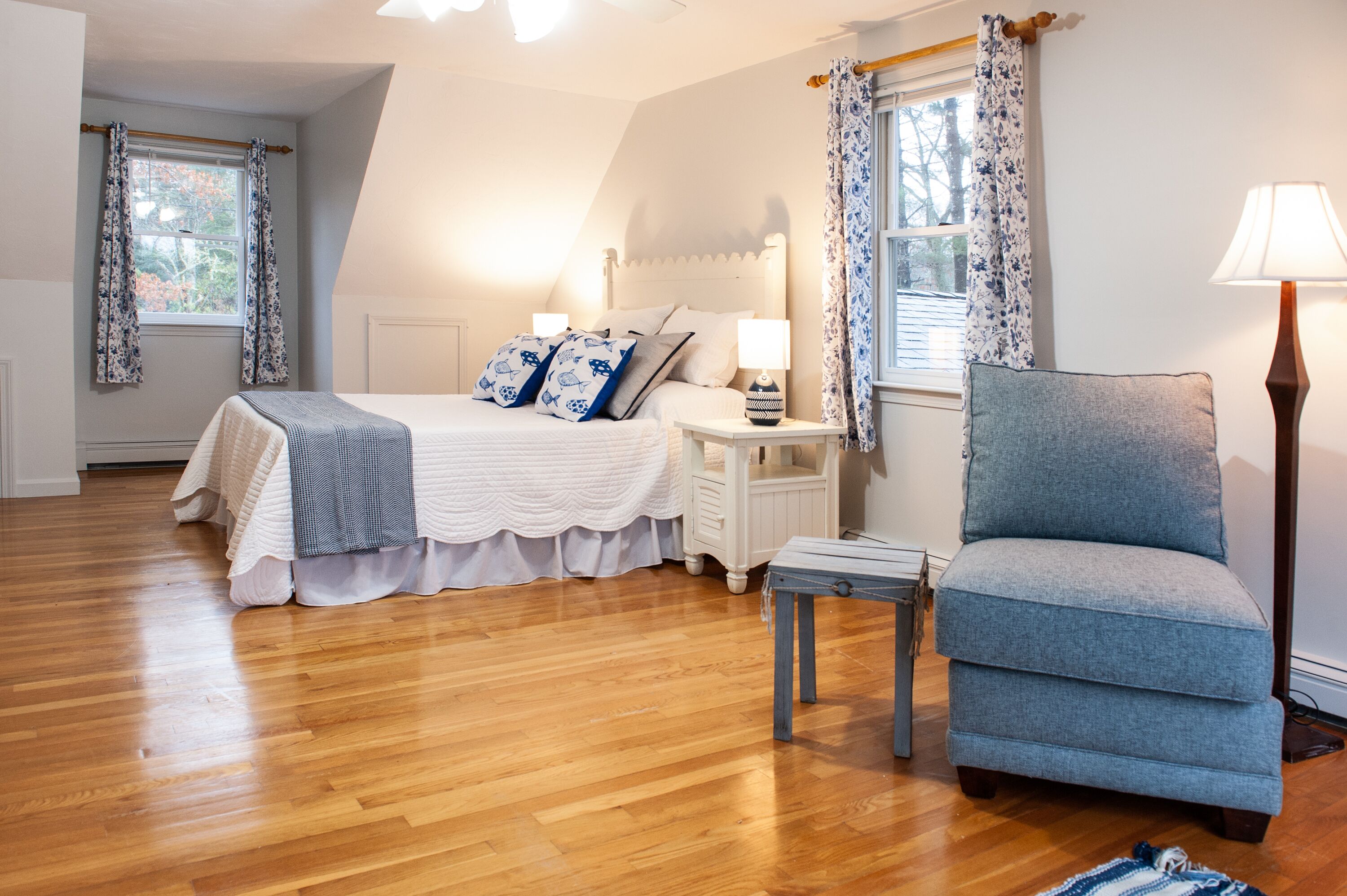 Une chambre à coucher avec un lit, des tables de chevet, une chaise et une lampe.