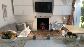 Un salon moderne doté d’une cheminée, d’un téléviseur à écran plat et d’un coin repas avec une table en bois.